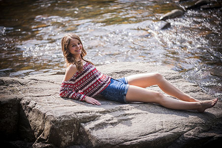 Young female lounging on a rock by a stream in Morrison, CO