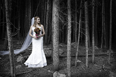 Bride in gown and bouquet standing in woods