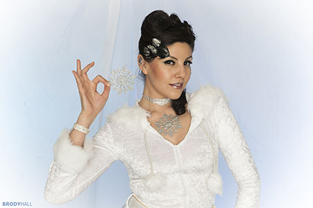 adult female in white winter outfit holding a snowflake in studio