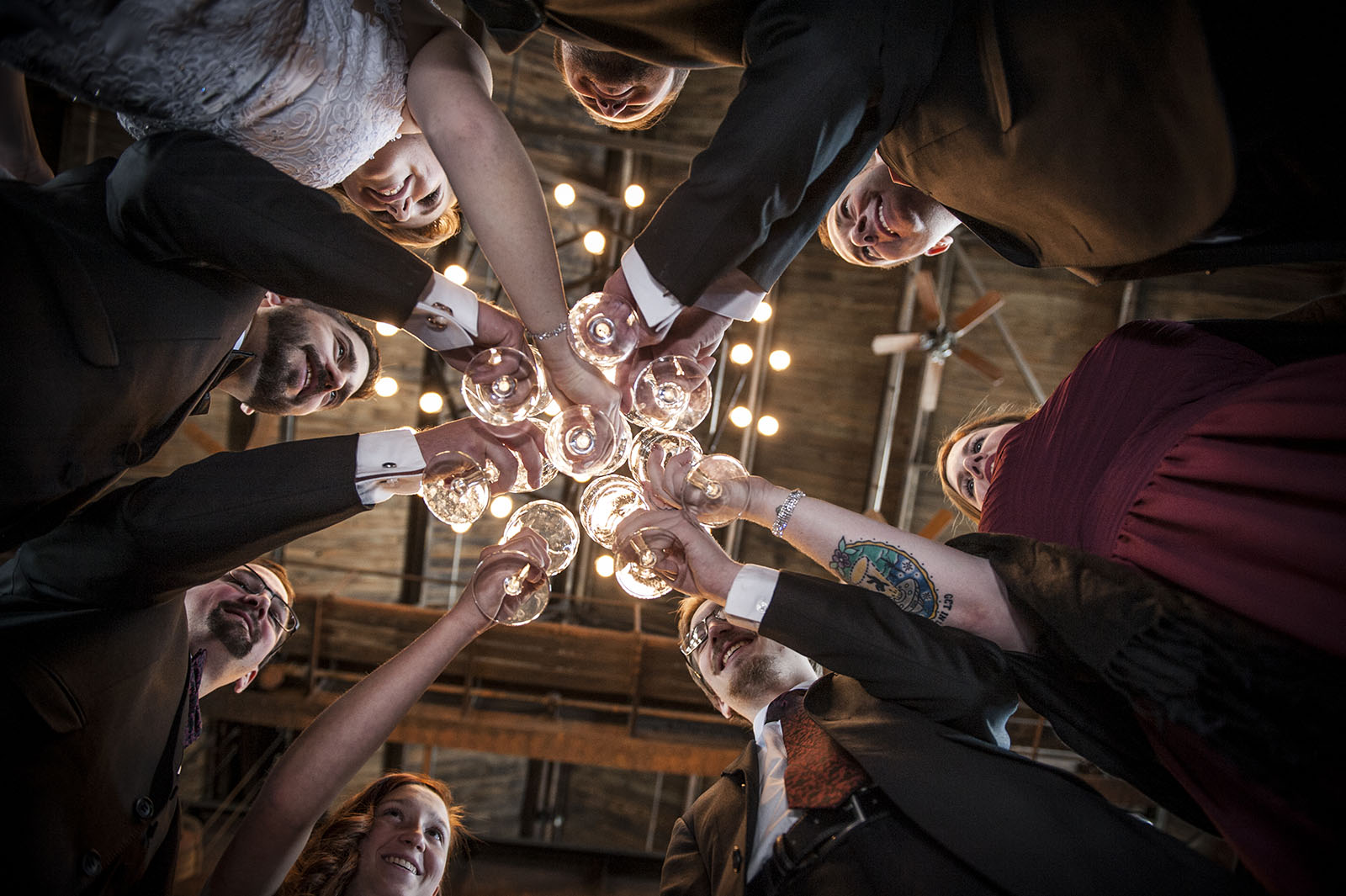 Bridal party clinking glasses at Mile High Station in Denver, CO, photographed from below