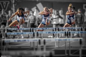Three girls running hurdles at Valor High School