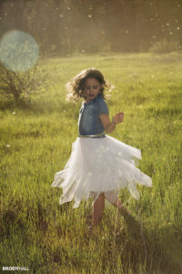 Lil girl twirling in green fields