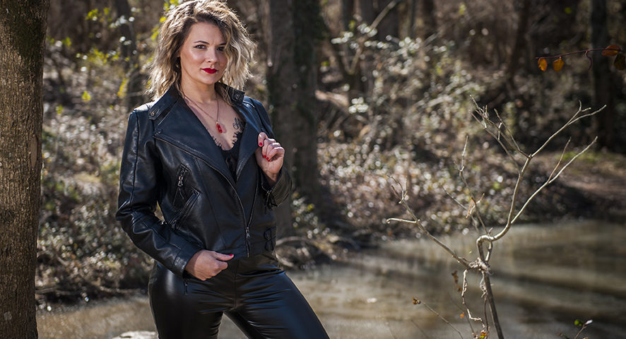Brittany in leather jacket and pants in woods.
