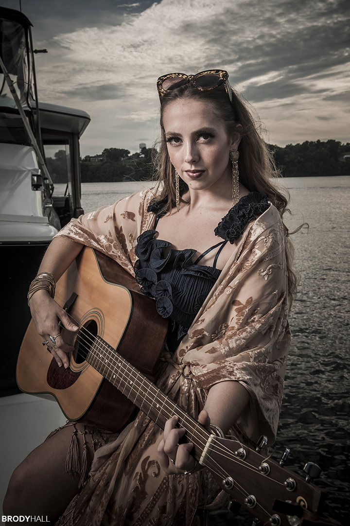 Angela playing a guitar on a boat