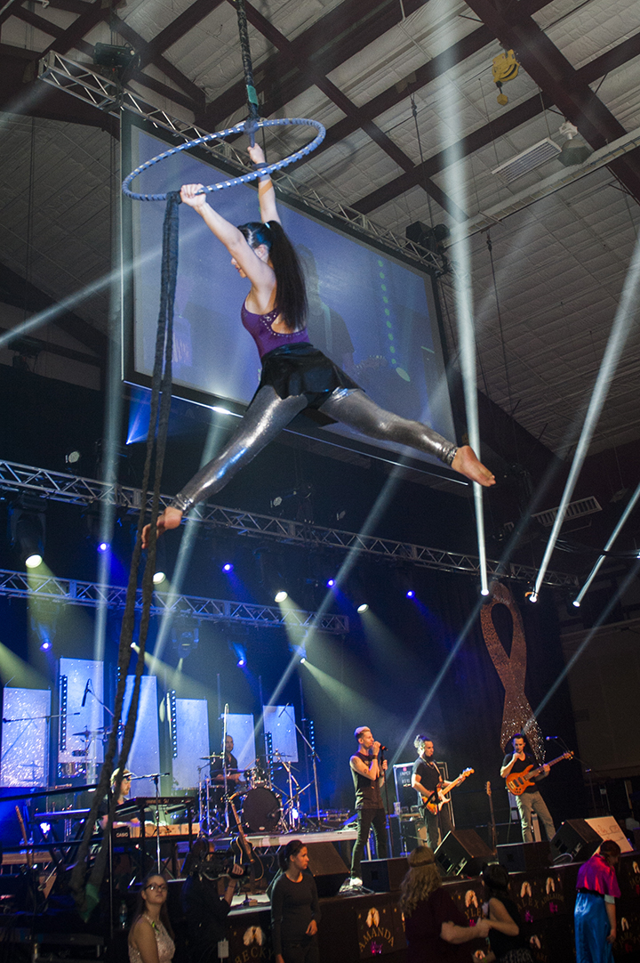 Aerial performer hanging above a band. Concert lighting in the backgrouind