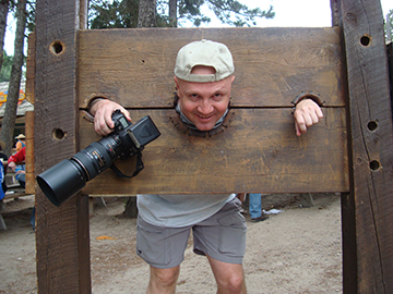 Brody in Wooden stocks holding camera