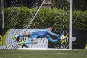 Soccer goalie diving to the far side and blocking a penalty kick shot!