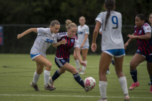 Two young female soccer players competing for the ball.