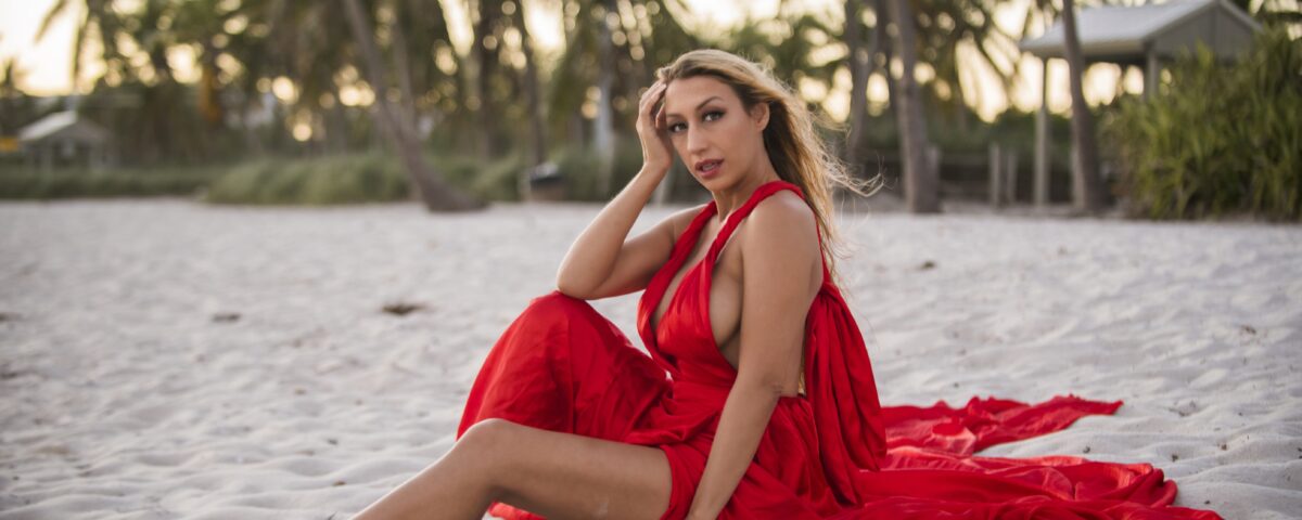 The beautiful model, Harlow Wilde, wearing a sexy satin dress sitting on the beach in Key West, Florida.