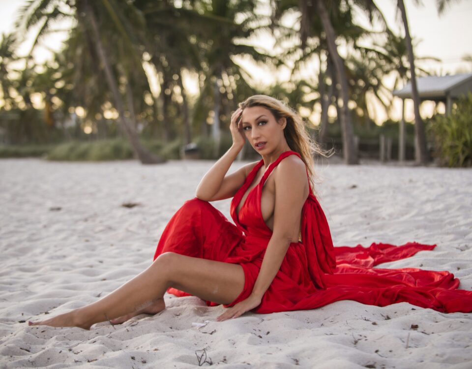 The beautiful model, Harlow Wilde, wearing a sexy satin dress sitting on the beach in Key West, Florida.