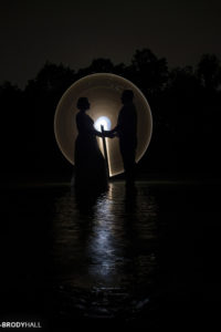 Silhoutte of two people holding hands with a dim light painting circle around them