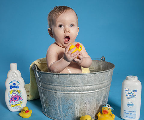 Baby Zen with a surprised look on his face as he takes a bath in studio, mom giving him a mow hawk.