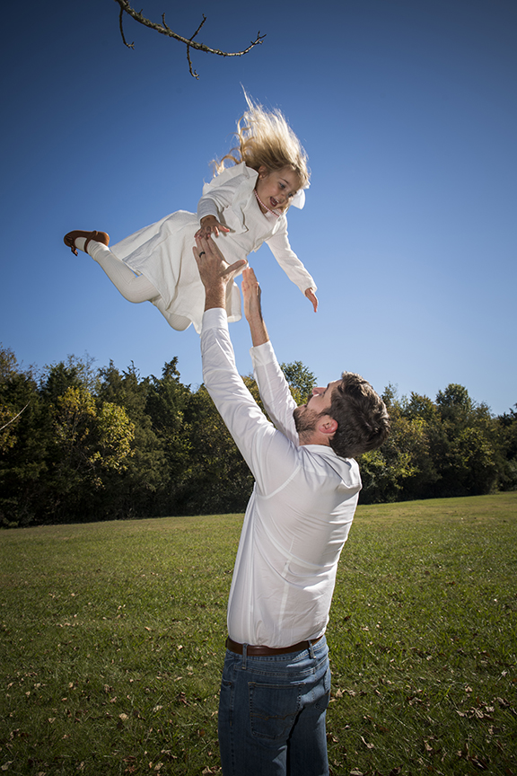 dad-tossing-daughter-in-air A dad, playfully, tossing his laughing daughter in the air, out in a park in Nashville.