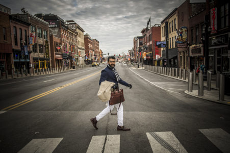 A man walking across Broadway in downtown Nashville