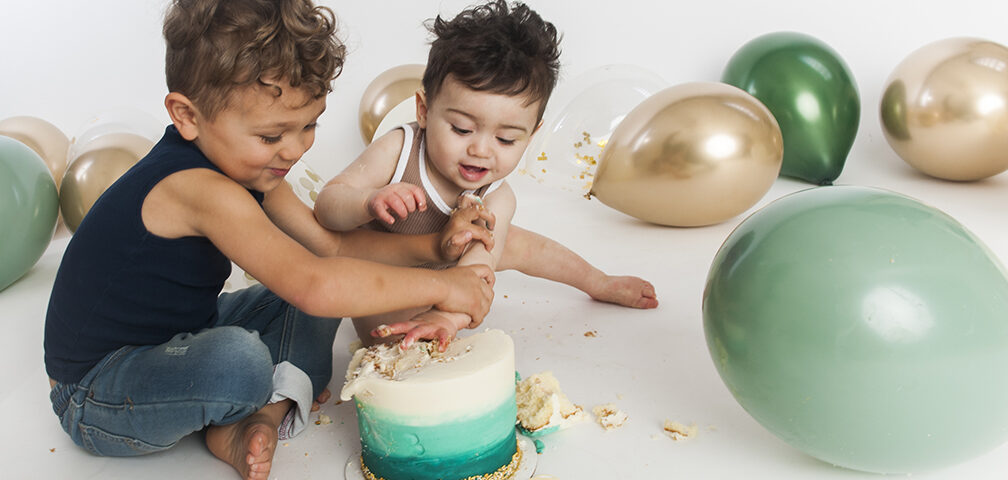 Two young brothers wrestling over a birthday cake.