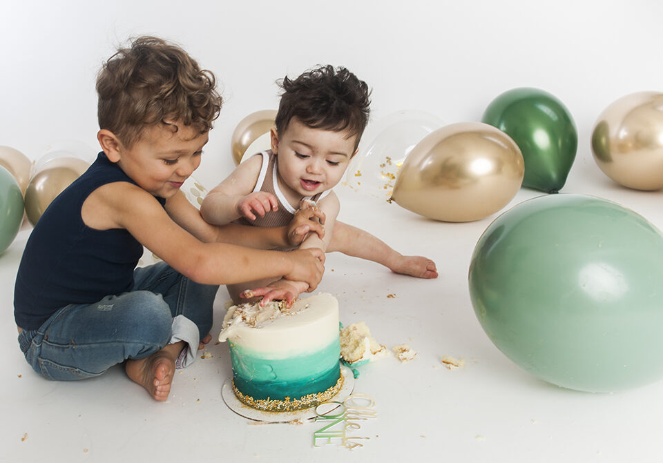 Two young brothers wrestling over a birthday cake.