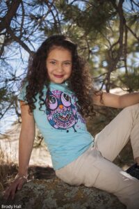Young girl sitting on a rock posing for the camera.