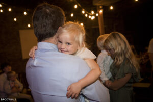 Dad and daughter dancing at wedding with the daughter smiling over dad's shoulder. 