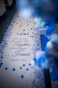 Custom blue-and-white wedding aisle runner decorated with rose petals for a Colorado church wedding.