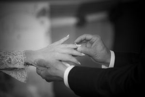Black-and-white close-up of a groom placing a wedding ring on his bride's finger during their Middle Tennessee wedding ceremony.