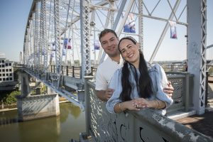 Yitzy and Leah smiling together on Nashville's John Seigenthaler Pedestrian Bridge during their couples photo shoot.